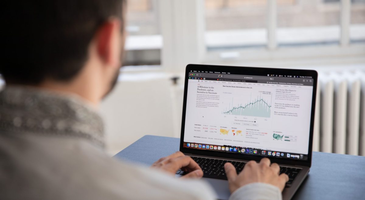A professional business analyst reviewing data charts and financial analytics on a laptop screen at a desk.